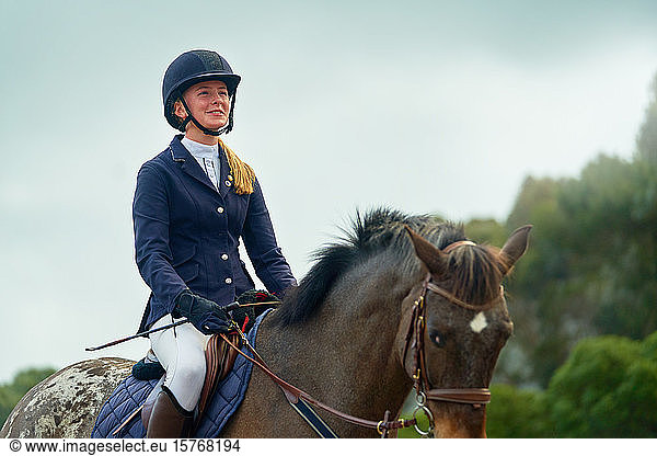 Confident smiling teenage girl equestrian horseback riding