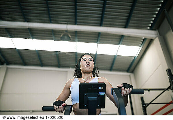 Confident sportswoman using exercise machine in gym