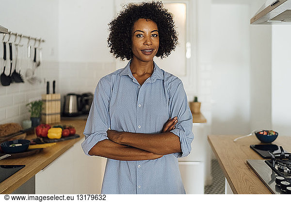 Confident woman standing in her kitchen with arms crossed