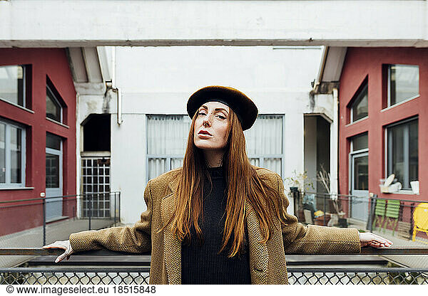 Confident woman wearing beret hat standing in front of railing