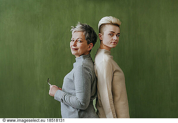 Confident women with short hair standing by green wall