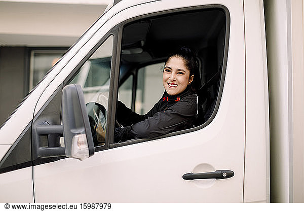 Confident young delivery woman driving truck