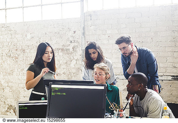 Confident young professionals planning while coding in computer at workplace