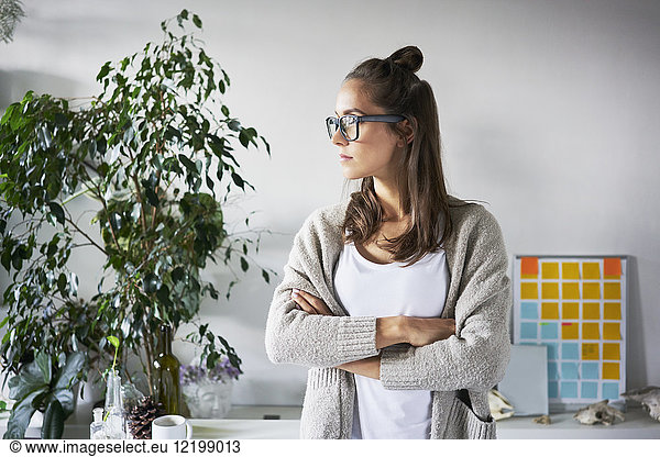 Confident young woman standing in office looking sideways