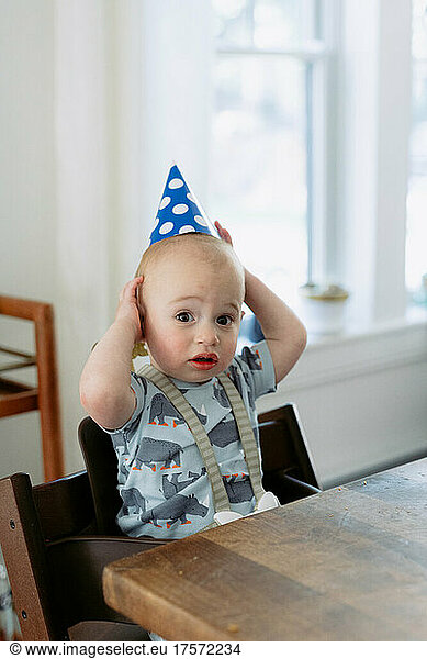 Confused one year old with party hat on his birthday