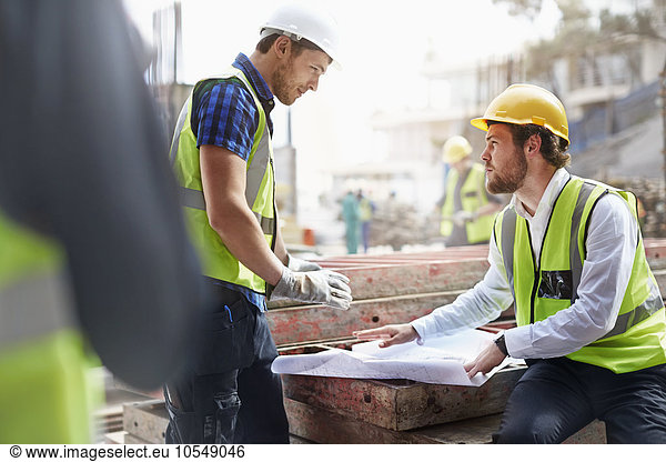 Construction worker and engineer reviewing blueprints at construction site