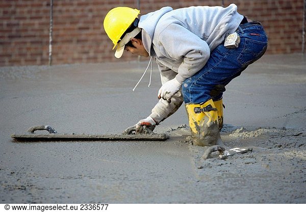 Construction worker smoothing concrete with masons float