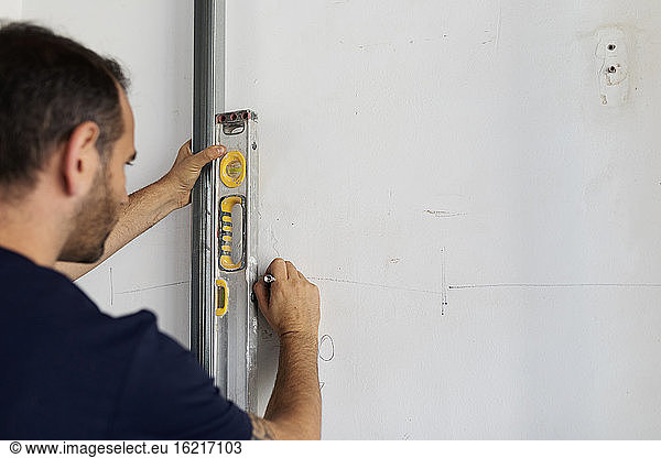 Construction worker taking marking at a wall