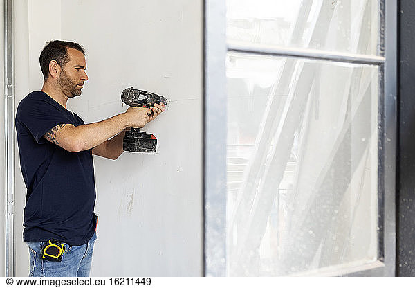 Construction worker using drill at a wall