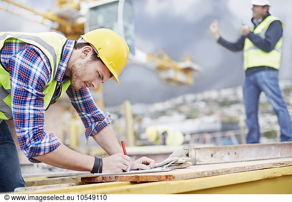 Construction worker writing on clipboard at construction site
