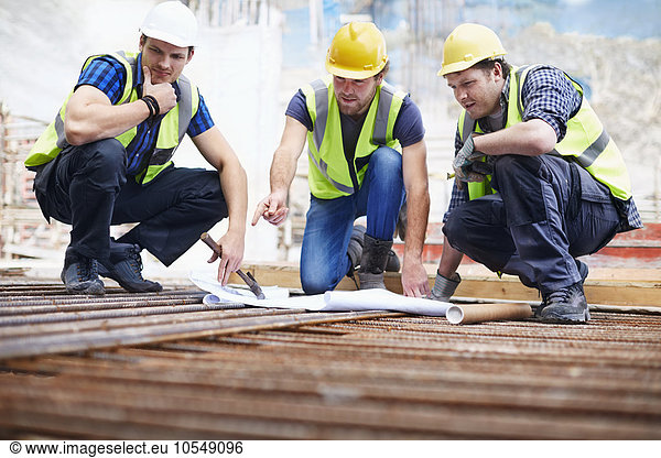 Construction workers and engineer reviewing blueprints at construction site