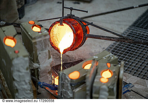 Container pouring melted bronze in workshop