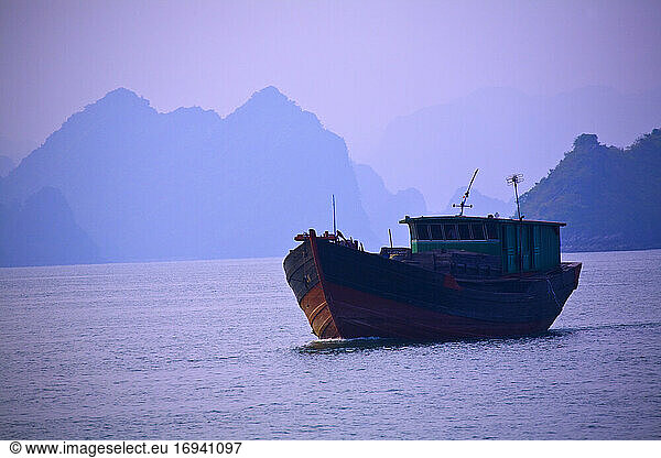 Container Ship on the water with mountains behind.