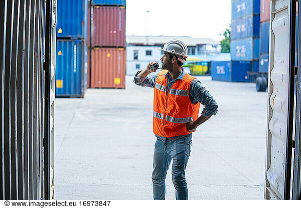 Container worker talking on the walkie-talkie at container wareh