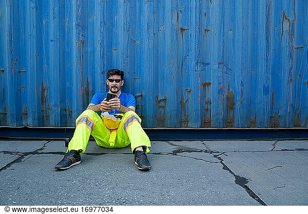 Containers worker sitting at container cargo area feeling sad an
