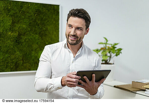 Contemplative businessman with tablet PC in office