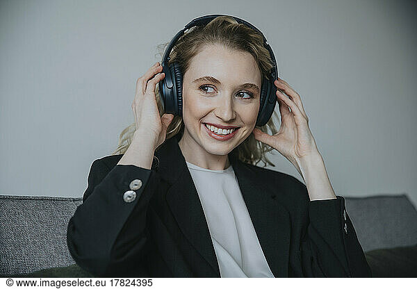 Contemplative businesswoman wearing wireless headphones