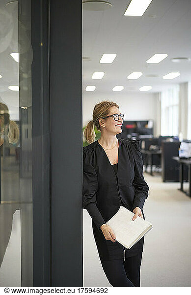 Contemplative businesswoman with document in office