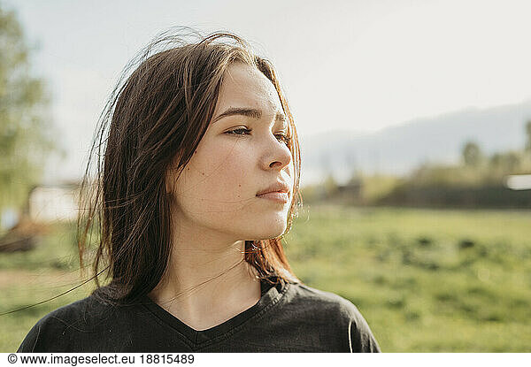 Contemplative girl with long hair in field