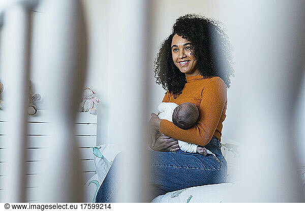 Contemplative mother breastfeeding son in bedroom