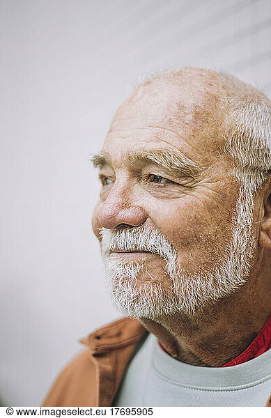 Contemplative senior man looking away against white background