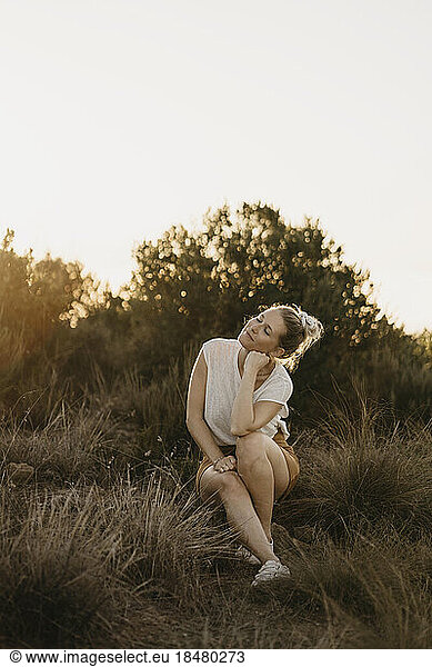 Contemplative woman leaning on elbow in park