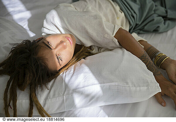 Contemplative woman lying on bed at home