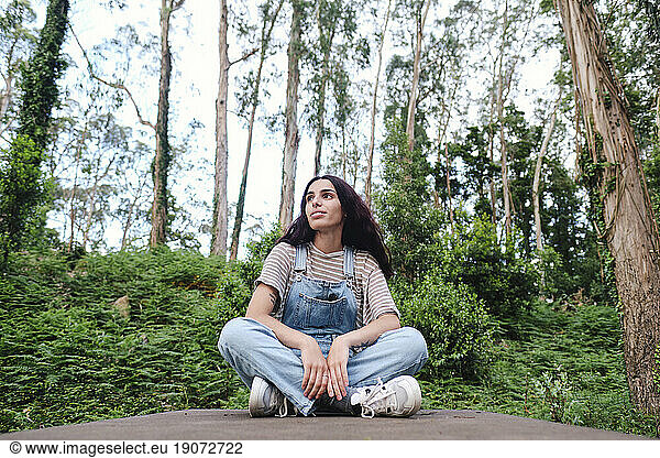 Contemplative woman sitting cross-legged in forest