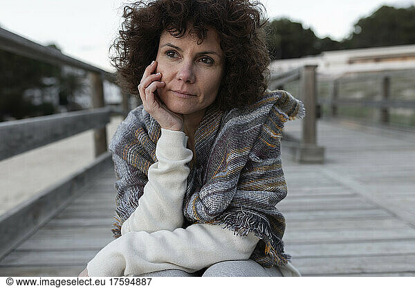 Contemplative woman sitting on footbridge in winter