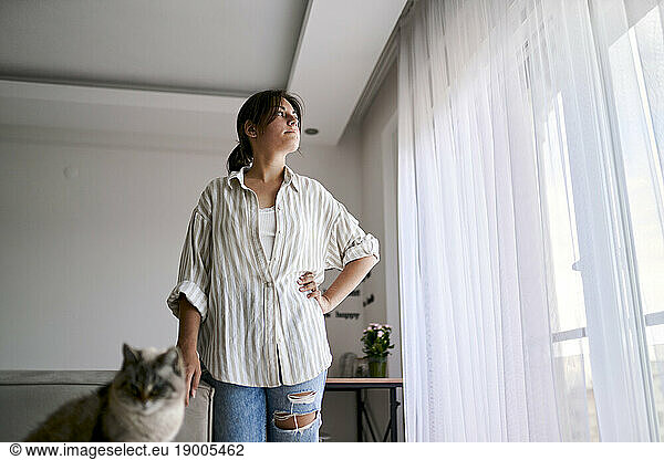 Contemplative woman standing by window at home