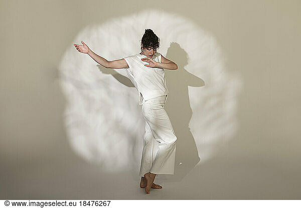 Contemporary dancer dancing against spotlight on brown background