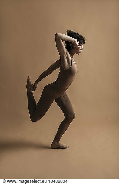 Contemporary dancer dancing over brown background