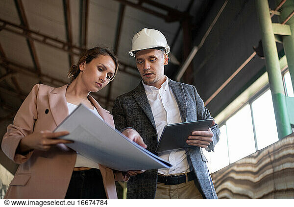 Contemporary engineers examining draft in warehouse building