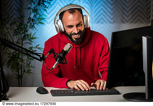 Content creator with headphones and microphone streaming a program online on the internet. Podcast presenter broadcasting on-air program. Content recording for internet program.