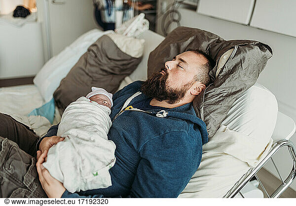 Content father resting after birth of newborn in birthing center