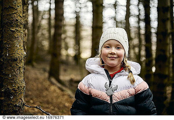 Content little girl chilling in autumn forest in daytime