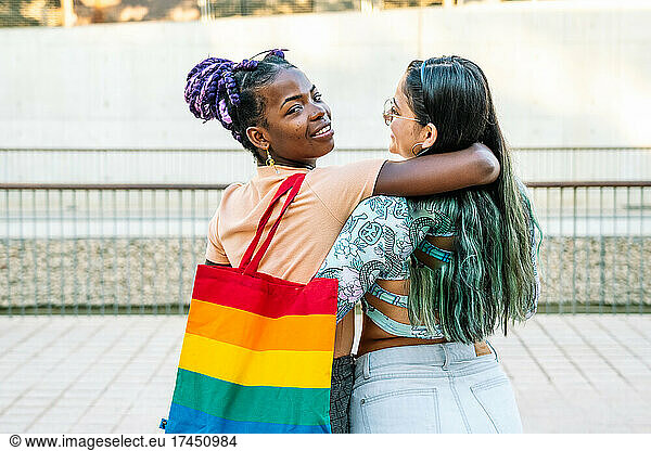 Content multiethnic lesbian girlfriends embracing on walkway