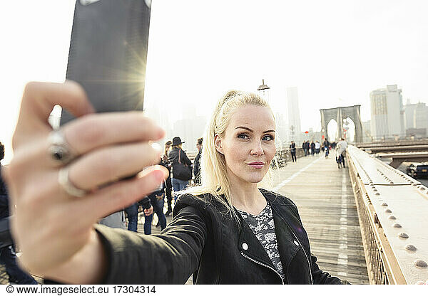 Content woman taking selfie on bridge in urban megapolis
