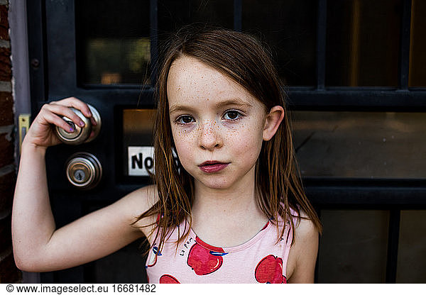 content young girl holding on to front door