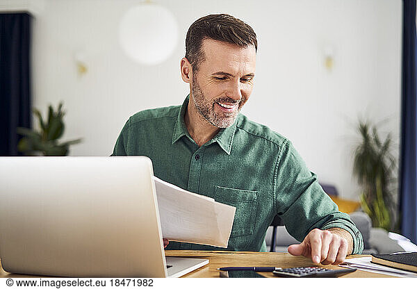 Contented man doing paperwork calculating finaces