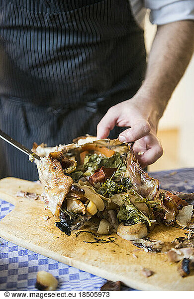 Cook carving a roasted duck with vegetable stuffing