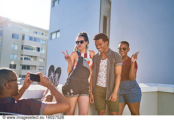 Cool playful young friends posing for photo on sunny rooftop