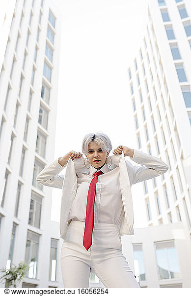 Cool young woman wearing white suit standing against buildings in city