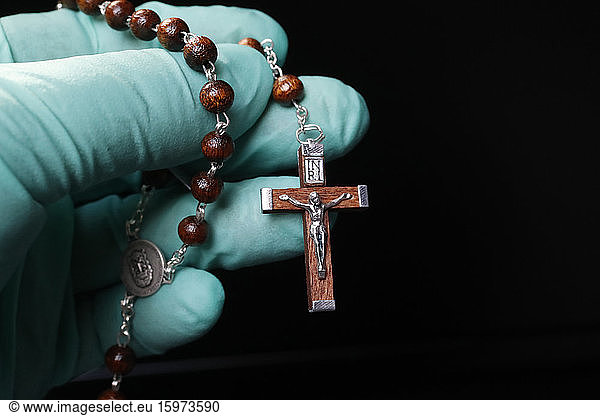Coronavirus (COVID-19)-Epidemie  Christen beten Rosenkranzperlen mit Schutzhandschuh  Frankreich  Europa
