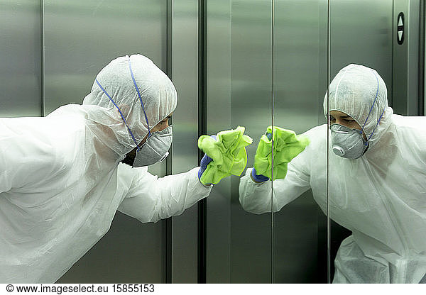 coronavirus. Worker disinfecting hospital elevator to avoid contagion.