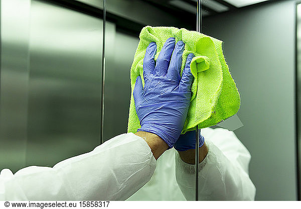 coronavirus. Worker disinfecting hospital elevator to avoid contagion.