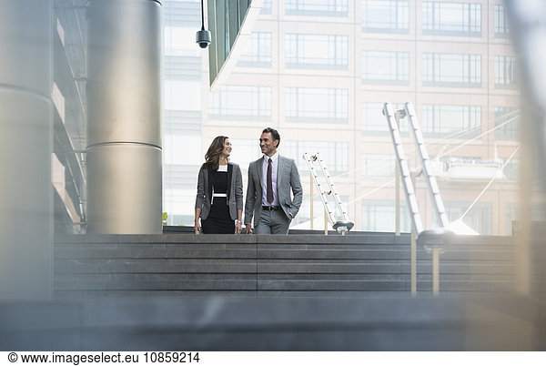 Corporate businessman and businesswoman descending stairs outdoors