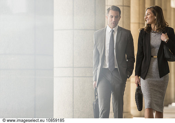 Corporate businessman and businesswoman walking and talking in cloister