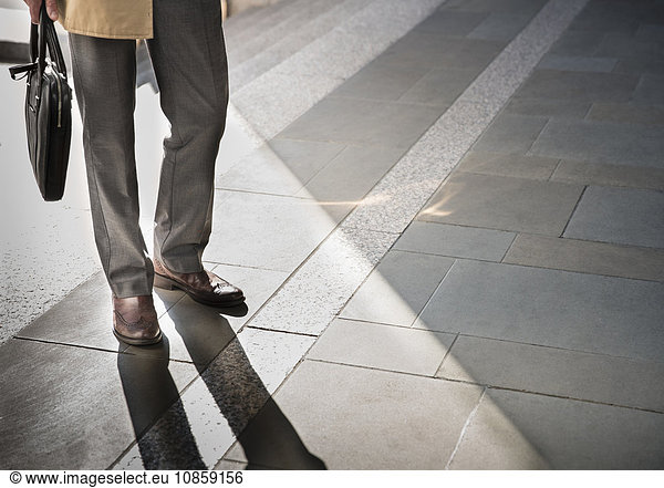 Corporate businessman standing on sunny pavement