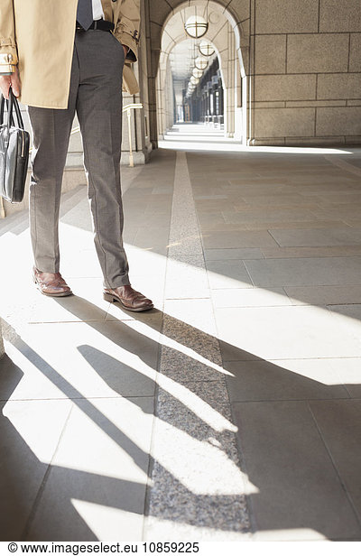 Corporate businessman walking in sunny cloister